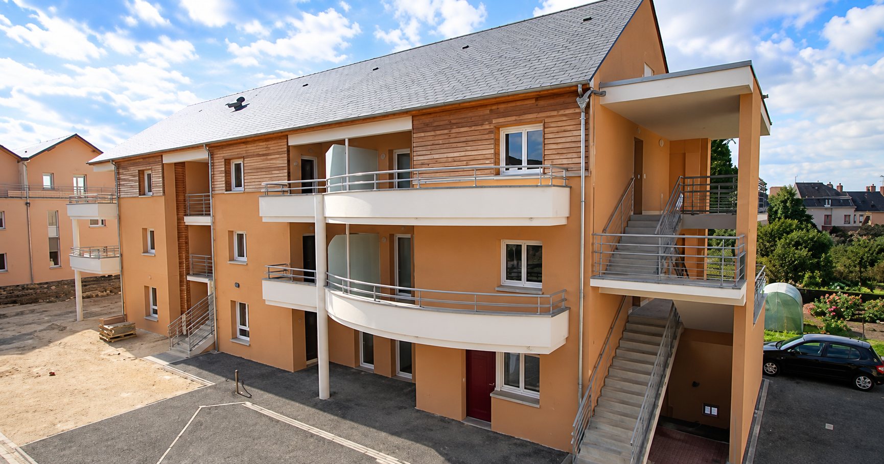 Immeuble résidentiel récent aux façades orangées et aux balcons.